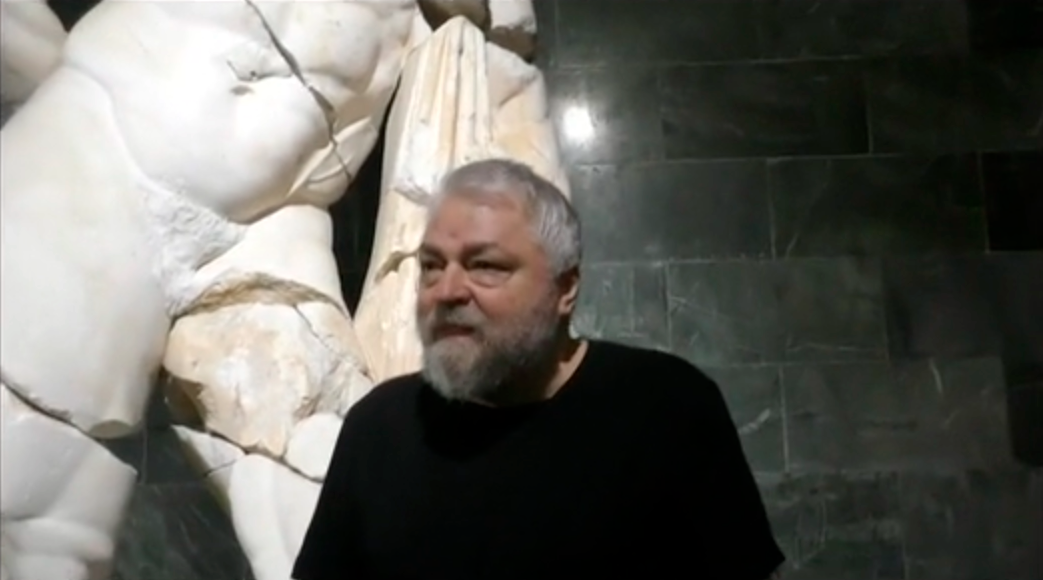 The writer Aleksei Meniailov is recording an interview against the backdrop of the statue of Heracles in the archaeological museum of Antalya for his video lecture "Centaur Nessus, Heracles, Deianira"